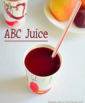 an abc juice cup with a straw in it and some fruit on the table next to it