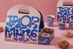 a pink table topped with donuts covered in frosting and sprinkles