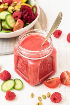 a bowl of fruit and vegetables next to a jar of strawberry cucumber sauce