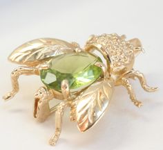 Bee Insect Pin Brooch 14k Gold Pin Pendant Peridot Semi Precious Gemstone Beautiful Bee Pin Brooch set with Peridot in 14k Gold Built in Bale to hang from a chain 14k Gold Peridot Insect Measures 15/16 Inch 2.4cm from Head to Tail Wingspan 13/16 Inch 2.05cm Peridot 8mm x 11mm Fine Jewelry Multi-stone Yellow Gold Brooches, Fine Jewelry Yellow Gold Multi-stone Brooches, Oval Yellow Gold Brooches With Gemstone, Fine Jewelry Green Gemstone Brooches, Heirloom Yellow Gold Gemstone Brooches, Yellow Gold Multi-stone Brooches As Gift, Collectible Gold Brooches With Gemstones, Fine Jewelry Green Brooches For Anniversary, Fine Jewelry Gold Brooches With Multi-stone