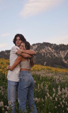 two people hugging each other in a field of flowers