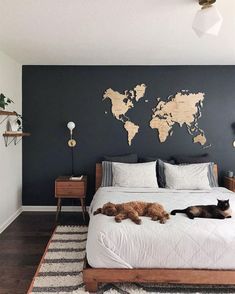 a cat laying on top of a bed next to a wall with a world map