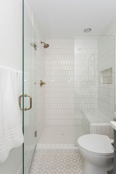 a white tiled bathroom with glass shower doors