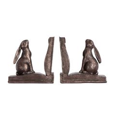 a pair of metal bookends with rabbits sitting on top of each other in front of a white background