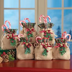 four bags with candy canes and christmas decorations on a table next to pine cones