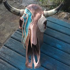 a cow's head with blue and white designs on it sitting on a wooden bench