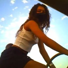 a woman riding on the back of a boat in the sun with her hands on the steering wheel