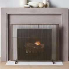 a fireplace with a fire in it sitting on top of a wooden floor next to vases