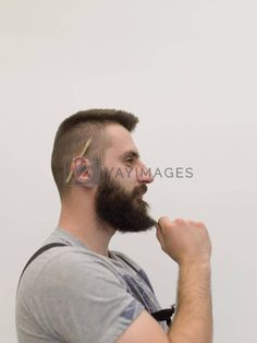 a man with a goatee combing his hair in front of a white background