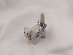 a white cat figurine with a ring on it's head