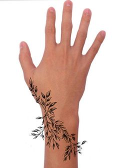 a person's hand with black ink on it and leaves around the wrist area