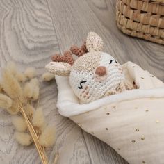 a crocheted stuffed animal laying on top of a blanket next to some dry grass