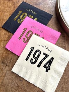 three napkins that are sitting on top of a wooden table, one with the number forty four printed on it