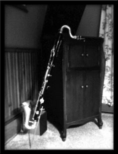 a black and white photo of a musical instrument leaning against a dresser in a bedroom