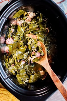 cooked collard greens in a crock pot with a wooden spoon on the side