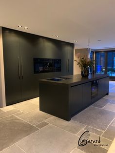 a large kitchen with black cabinets and an island in front of a window that looks out onto the street