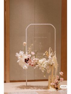 an arrangement of flowers is displayed in front of a glass display case on the floor