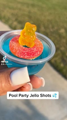 a person is holding a small plastic toy bear in a pool party jello shots