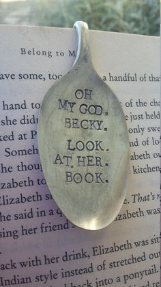 a spoon that is sitting on top of an open book with the words oh my god, look at her book