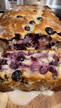 a loaf of blueberry bread sitting on top of a wooden cutting board