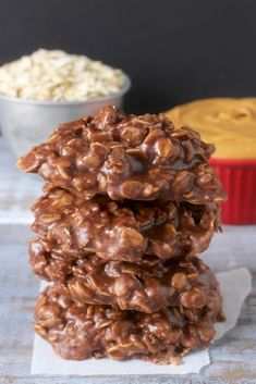 three cookies stacked on top of each other next to a bowl of oatmeal