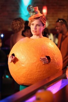 a woman in a costume holding an orange