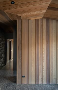 an empty room with wood paneling on the walls and floor is seen in this image