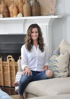 a woman sitting on top of a couch next to a fire place