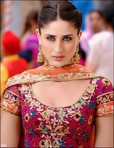 a woman in a red and gold dress with large earrings on her head, looking at the camera