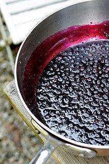 a metal pot filled with liquid sitting on top of a wooden table