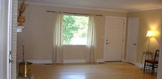 an empty living room with hard wood floors and white walls, two doors open to the outside