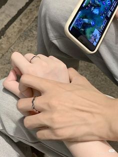 two hands holding onto each other while using a cell phone with the screen turned on