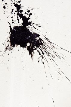 black ink splattered on white paper with an object in the foreground that appears to be falling