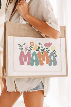 a woman carrying a bag with the word mama printed on it and flowers in the letters