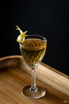 a glass filled with liquid sitting on top of a wooden tray