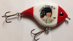 a red and white fishing lure with a picture of a woman on it's side