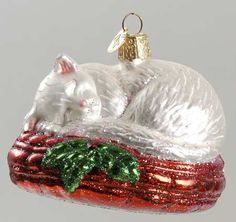 a glass ornament shaped like a cat sleeping on top of a christmas tree