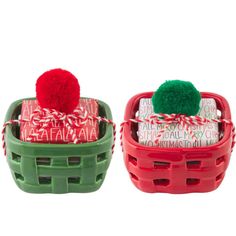 two baskets with christmas wrapping and pom - poms on them, one is green and the other is red