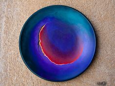 a blue plate with red and yellow designs on the rim sits on a tan surface