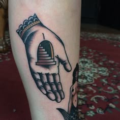 a person with a tattoo on their leg that has a hand holding a bell in it