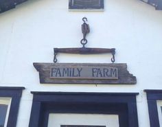 a sign that says family farm hanging from the side of a white building with black trim