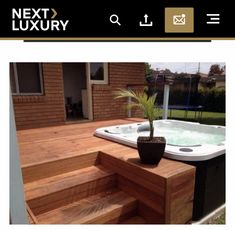 a hot tub sitting on top of a wooden deck next to a tree in a pot