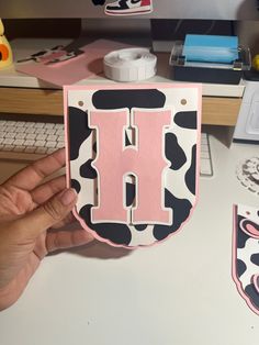 a person holding up a pink and black letter shaped box with the letter h on it