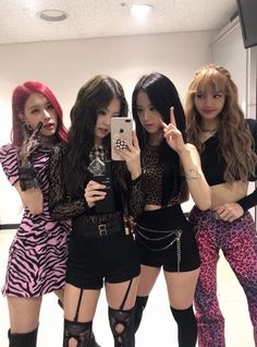 four girls are posing in front of a mirror