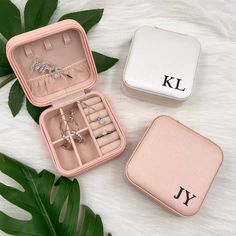 three jewelry boxes with personalized rings in them on a furnishing floor next to leaves