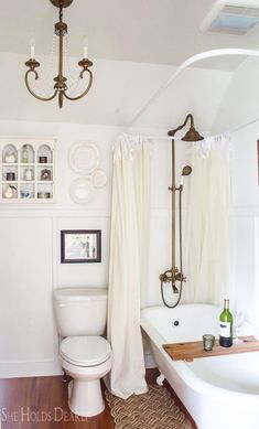 a bathroom with a tub, toilet and chandelier hanging from it's ceiling