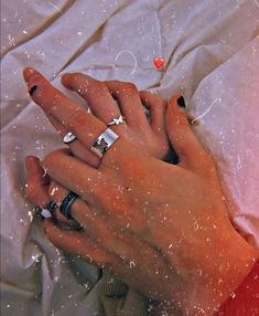 a woman's hand with two rings on it and hearts floating in the air