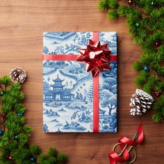 a gift wrapped in blue and white with a red bow on it, surrounded by christmas decorations