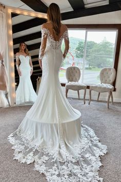 a woman in a wedding dress looking at herself in the mirror