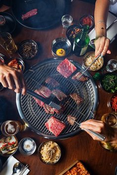 people are grilling steaks on a bbq with chopsticks in their hands